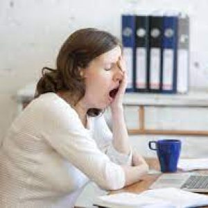 a women sitting at a desk yawning